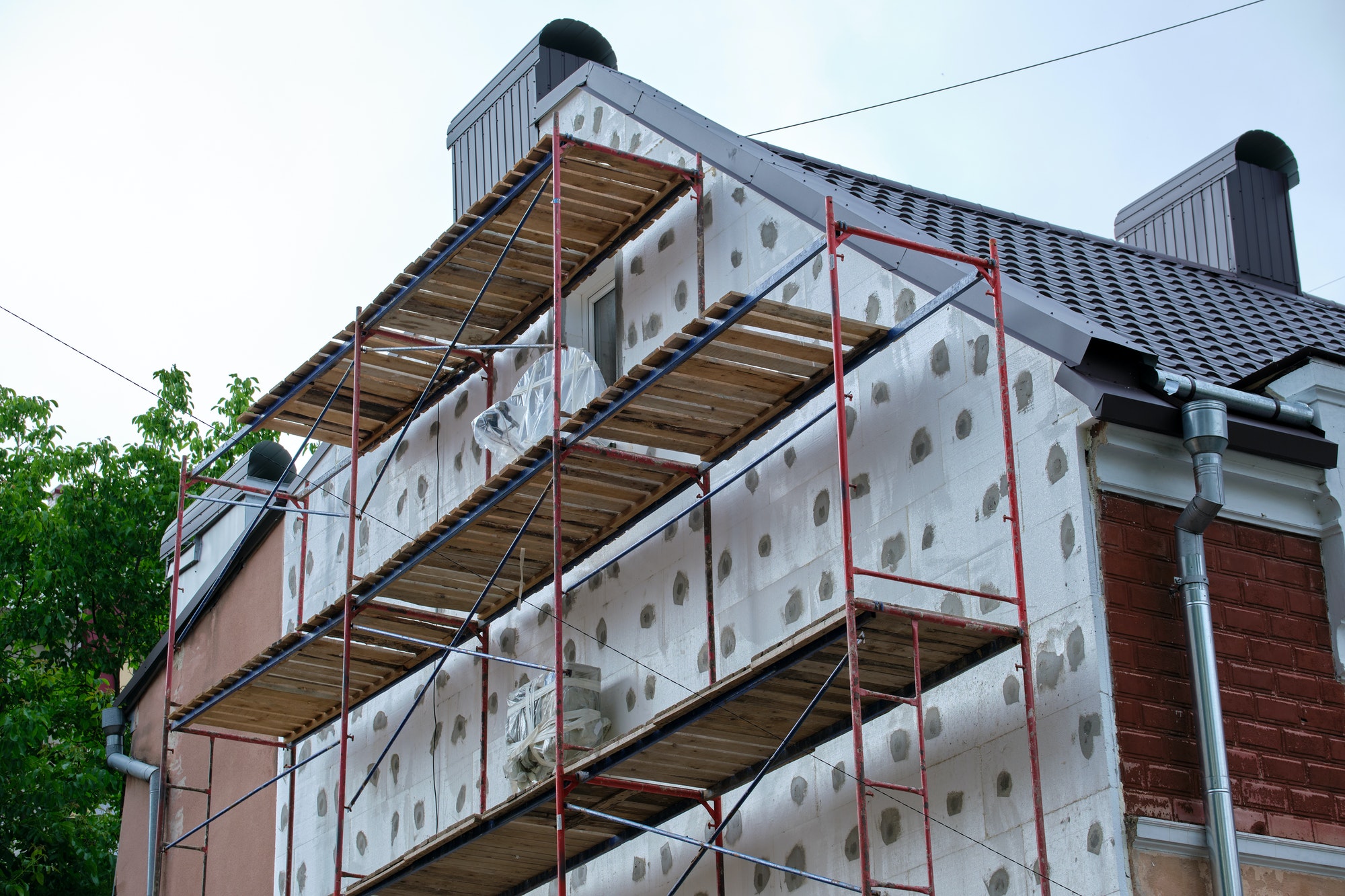 Building facade under renovation works with construction scaffolding frame.