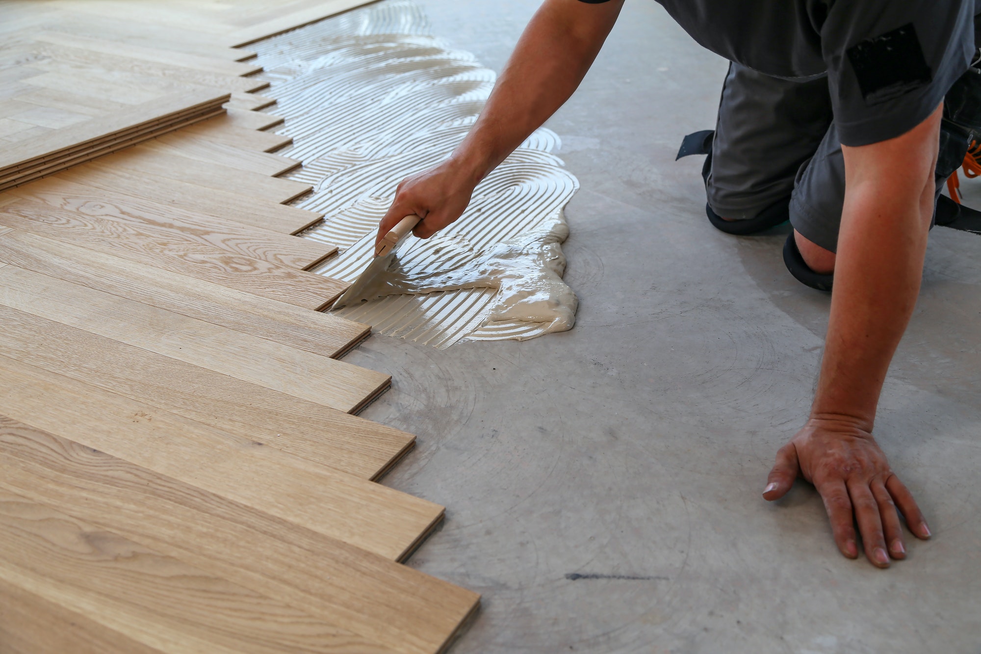 Male worker installing a wooden laminate flooring on his knees